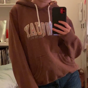 Hoodie - Cool brun hoodie med text. Köpt secondhand, är i storlek 42 men tror inte det är vanliga 42 skulle mer säga att den är xs/s. Möts upp i Stockholm eller står köparen för frakt.