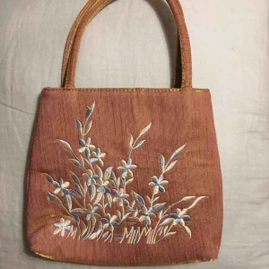  - Superfin väska i lite guldskimrande material med fin brodyr i pastellfärger💘 Köpt secondhand i nyskick. Säljer då den inte kommer till användning tyvärr. Möts eller fraktar!