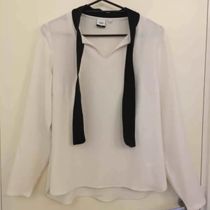  - Fin blus som går att knyta i en rosett vid halsen. 