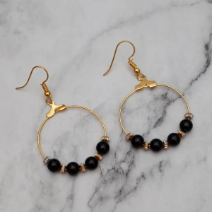  - Fina guldfärgade örhängen med svarta pärlor. Nickelfria.  Obs! Örhängena är inte orangea som på bilden, Photoshop ändrar färgerna för mig 🙃 Fri frakt vid köp över 100:-.