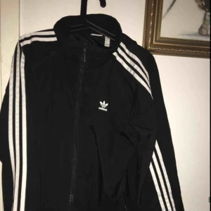  - Säljer en adidas vindjacka med luva. Stort tryck på ryggen. Sparsamt använd och bättre bilder är bara att fråga om!  Storlek M (40)  Frakt tillkommer på 55kr. 