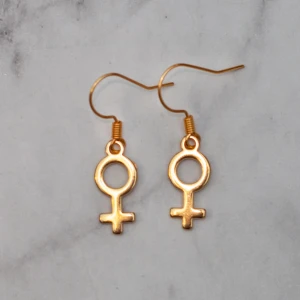  - Fina guldfärgade örhängen med kvinnosymbolen. Finns även som silverfärgade. Nickelfria. Obs! De är inte orangea som på bilden, Photoshop ändrar färgerna för mig 🙃 Fri frakt vid köp över 100:-.