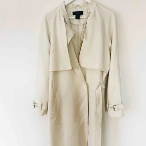  - Vit kappa från ellos, strl 40.  Knappar samt band i midjan.  Spänndetalj i ärmslut och spänndetalj vid krage. 