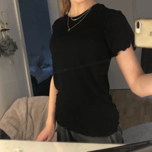 Svart t-shirt - En svart t-shirt med volanger på armarna och längst nere i storlek xs (helt ny endast testad)