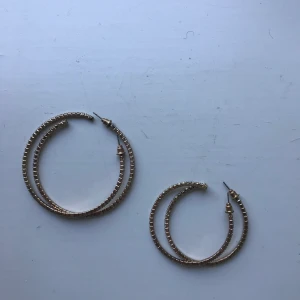 Örhängen - Två par guldiga örhängen med diamantliknande stenar. De stora är aldrig använda och de små är endast använda 1 gång. Båda paren är inkluderade i priset. Frakt inkluderat i priset!