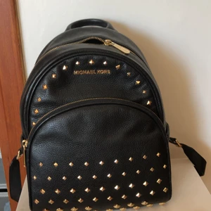 michael kors - äkta michael kors köpte året innan den röda på samma ställe den har gått sönder lite men en nitt liger i fram fickan ifall man vill testa att sätta på den.  den var dyrare en den röda när jag köpte den därför är det nästan samma pris