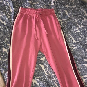 Rosa byxor S - Rosa högmidjade mjukings byxor med lila och vitt sträck på sidorna, storlek S, jätte sköna!! Du står för frakten!