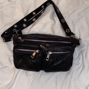 Noella Väska Celina I Läder - Mellan storleken i läder med ett detaljerat väskband. Även att den är liten så får du plats med extremt mycket saker.