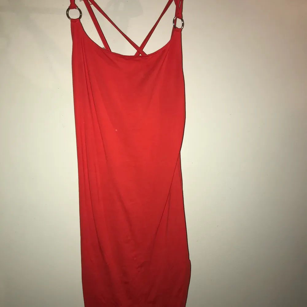 Röd klänning med korsande band i ryggen och ringar . Klänningar.