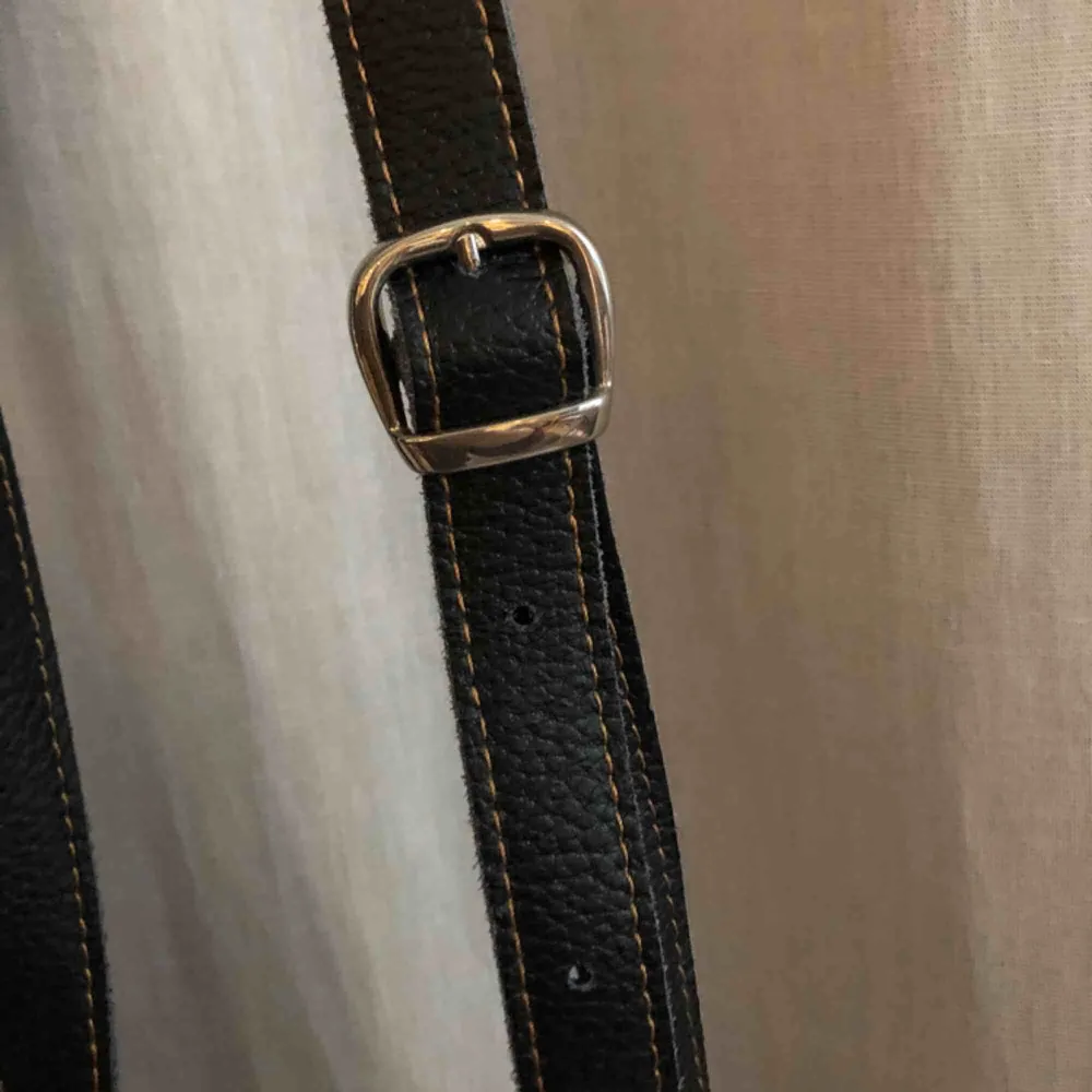 En svart vintage axelremsväska i äkta skin med justerbar axelrem, köpt secondhand men i fint skick!  Möts upp i Stockholm eller så står köparen för fraktkostnader             Priset kan diskuteras . Väskor.