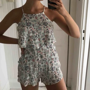  - Söt somrig jumpsuit med blommönster i fina ljusa färger. Djup i ryggen och högre i halsen. Sval och perfekt till stranden! Knappt använd👍🌞