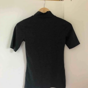  - Mörkgrå polotröja från Gina Tricot i storlek S