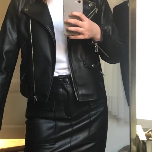 Kort ”skinnkjol” från zara - Cool kjol i fake-skinn från zara. Normal i storleken. Snygga detaljer och är superfin till vit topp, skinnjacka och vita sneakers.