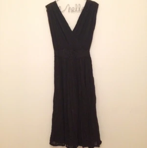  - Svart klänning i grekisk stil, v-ringad både fram och i ryggen. Ankellång. Fin dekoration med broderi i midjan.