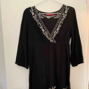  - Kortare svart klänning med vita broderi detaljer.  Halvlånga ärmar.   Porto betalas av köparen.  