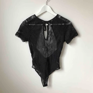 - Svart spetsbody med öppen rygg i mycket fint skick. Köparen står för fraktkostnad enligt postens portotabell.