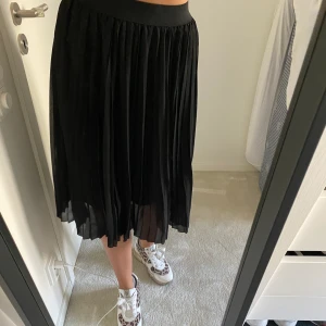 Plisserad kjol från NAKD - Modern Svart kjol från NAKD, går lite över knäna & är skön & fin 