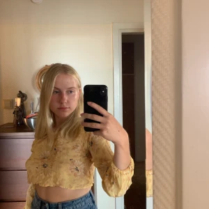 Crop top S/SX - Jättesöt gul polyester topp med blommor på 🌼 Säljer den för att få plats i garderoben! Den är ganska kort så passar på folk med små bröst haha