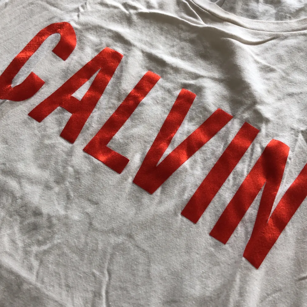 Offwhite Calvin T-shirt med röd glansig text. Använd ca 2 gånger. Liten fläck vid nedre sömmen se bilder. Frakten är inräknad i priset!. T-shirts.