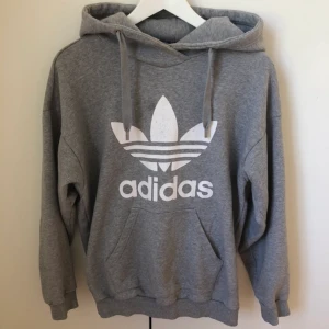 Adidas hoodie - Grå adidas hoodie i storlek 34 (är väldigt oversize så passar större), lite sliten på märket då den är använd mycket men annars i fint skick.