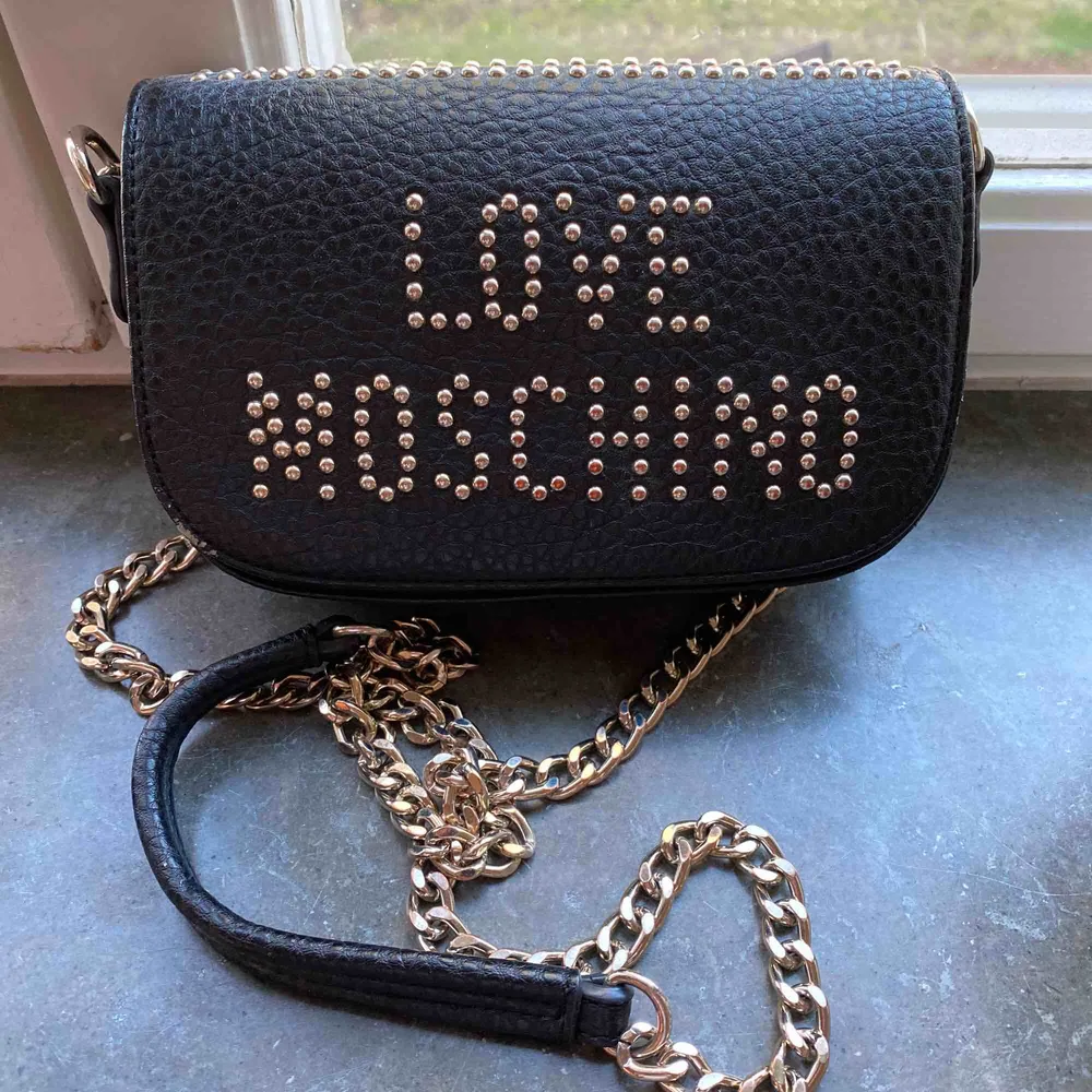 ÄKTA. Superfin väska från Love Moschino som köptes från Boozt för ca 2 år sedan för ca 1500kr. Säljer pga jag inte använder den längre. Bra skick förutom att det har lossnat lite på två ställen, se andra och sista bilden. . Väskor.