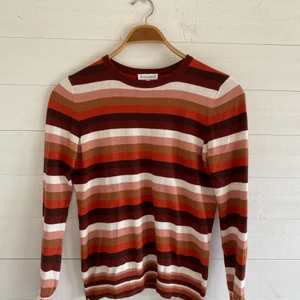 Stickad tröja - Randig stickad tröja med färgerna orange, brun och beige. Mycket bra skick! Originalpris: 300 kr