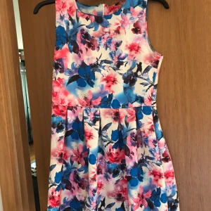 Somrig klänning - En blommig klänning som är för någon som antingen är kortare eller smalare än vad jag är. Klänningen är väldigt kort och skulle nog passa någon i strl. S-M. Fint skick. Köpare står för frakt.