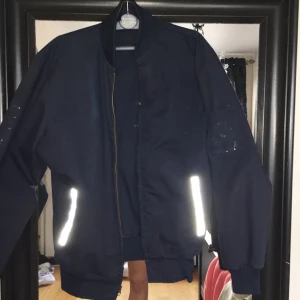  - En mörkblå tygjacka. Reflexen vid fickorna. Köpt på beyond retro 