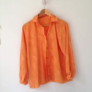 Orange skjorta i silkigt material. Använd ett fåtal gånger.