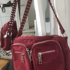 Noella väska - Säljer min vinröda noella väska. Båda banden ingår! Inte alls mycket använd och jätte bra skick! Står ej för frakt!💕