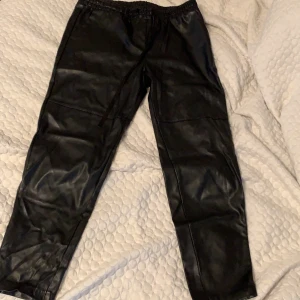 Svarta byxor i skinnimitation  - Svarta byxor i skinnimitation, lite oversize modell. Jättebra skick, använda några gånger . 