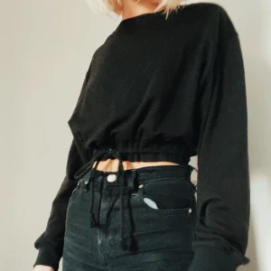 Svart sweatshirt  - Svart croppad sweatshirt från PacSun’s ”Me to We” kollektion. Drawstrings framtill. 