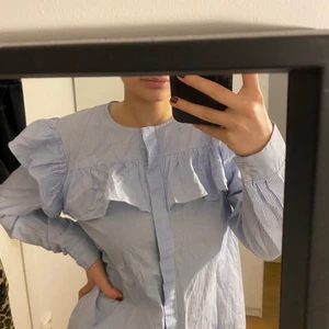 Blå skjorta - En blå skjorta med volanger. Lite tight så passar storlek S