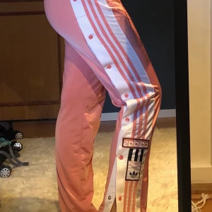 Adidas popper pants - Jättecoola rosa byxor från adidas med knappar på sidorna. Är i bra skick och är väldigt bekväma!