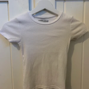 Vit T-shirt - En vit topp i storlek xs men enligt mig mer en xxs eftersom den inte passar mig som vanligtvis har storlek xs. Köparen står för frakten.