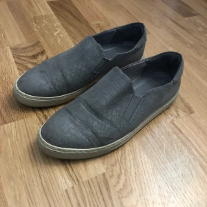 Grå slip-ons strl 39 - Köpta i en liten butik i Tyskland. Använda 1 sommar så inte nyskick men inget fel på dem.