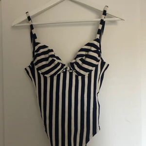 Retro baddräkt/body - Retro vit&marinblå-randig baddräkt som funkar lika bra som body. Djup i ryggen! Inbyggda kupor som jag skulle säga är I strl A eller liten B. Jätteskönt stretchigt material🌊🌞