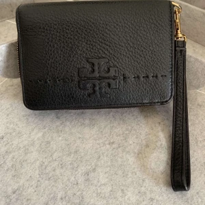 Tory Burch  - Svart plånbok med handtag av märkte Tory Burch. Köpte från Zalando.  Ord pris: ca 2000kr