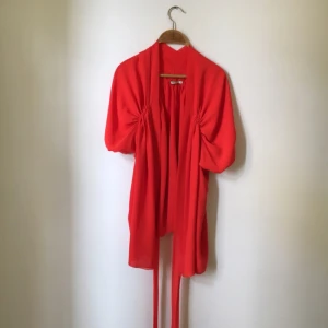  - Söt korallröd omlott topp från Lindex med detaljer sydda i resår som skapar en effektfull drapering! 