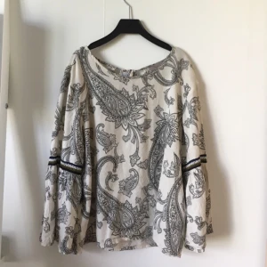  - Söt blus med mönster på. Armarna är typ 2/3 längd på och blir vidare i slutet och slutar ungefär efter armbågen . Väldigt enkel att bara slänga på och matcha med ett par jeans 