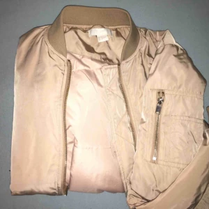 Beige Höstjacka/bomberjacka - En snygg beige/guldig bomberjacka som passar fint för många stilar. Supernajs till sommarkvällar, våren eller hösten!