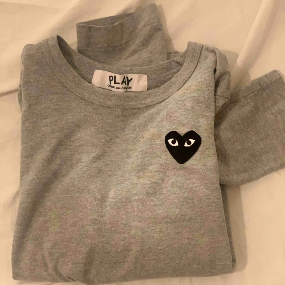 Äkta långärmad tröja från CDG (Comme des garcons). Säljer pga att den är för liten.. CDG är små i storlekarna så detta passar en som har XS eller liten S. tröjan är använd men i väldigt fint skick.  Kan skickas mot fraktkostnad, betalas av köpare. . Toppar.