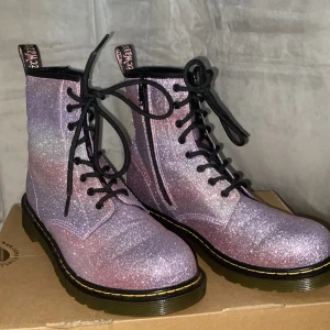 Dr martens - Rosa/lila glitter dr martens oanvända!! Säljer för dom inte kommit till andvänding! Köpta för ca 1500kr och säljer dom för 900kr + frakt eller mötas i sthlm city! Betalning via swish✨
