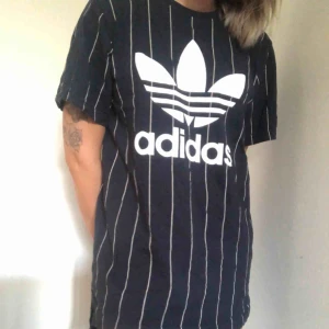  - Längre baseball inspirerad t-shirt från Adidas. Mörkblå med vita ränder. Kan använda som klänning eller som en längre t-shirt. Fint skick, knappt använd. 