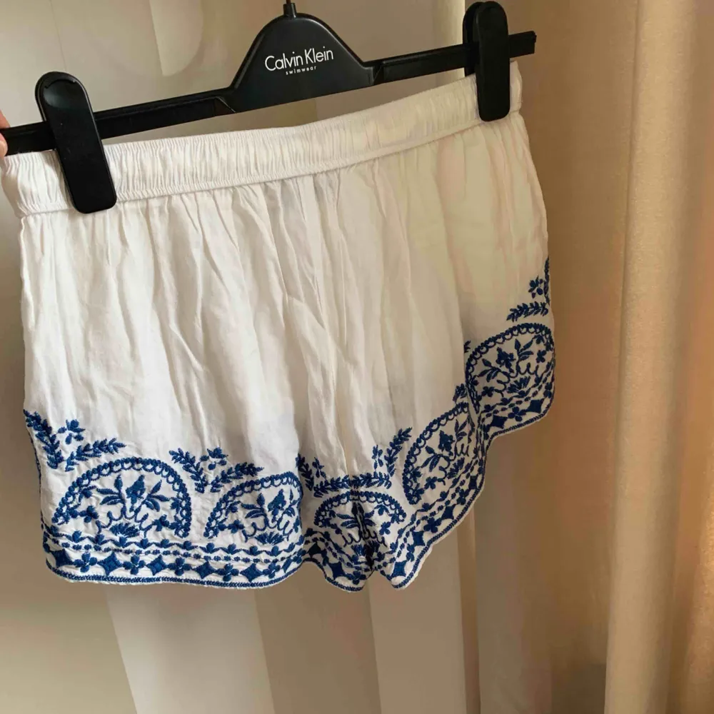 Vita shorts med blå broderade detaljer ifrån Gina Tricot! Använda väldigt få gånger och är i fint skick.  Strl S! Hör gärna av er vid frågor eller önskan om fler bilder!❤️. Shorts.