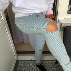  - Oanvända ,högmidjade, hollisterjeans i stolek 27. Hål på knäna, ”låssas” fickor fram och vanliga fickor bak. De är vit och blå randiga. 