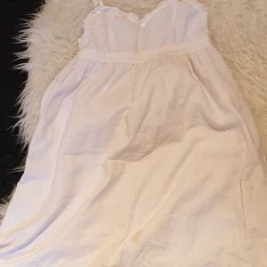  - En fin vit klänning som har vita prickar bra skick en svart kjol som är i bra skick och en grå bacik kofta