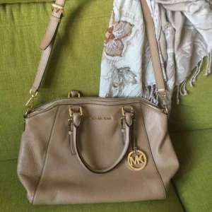  - Superfin Michael Kors-väska i nyskick. Mkt fräsch inuti. ”Bottenplattan” har små ”fötter” i metall. Måtten på botten är 35x12 cm. Ca 27 cm hög. Handtag o axelrem.