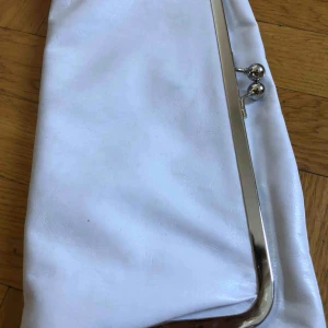  - En kuvertväska i hyfsat bra skick, den har endast några små missfärgningar från metallen. Den är 30 cm hög, 14 cm när den sitter ihop och 27 när den är utfälld. Lila innerfoder. Frakt ingår 