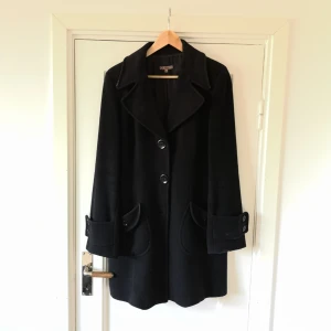  - Ullkappa med stora knappar. Jättefin passform! En knapp har lossnat men är lätt att sy på igen. Två extra knappar följer med. Kappan är också lite sönder i silkesfodret, därav det låga priset. Köpt för några år sedan för 1500 kr. 